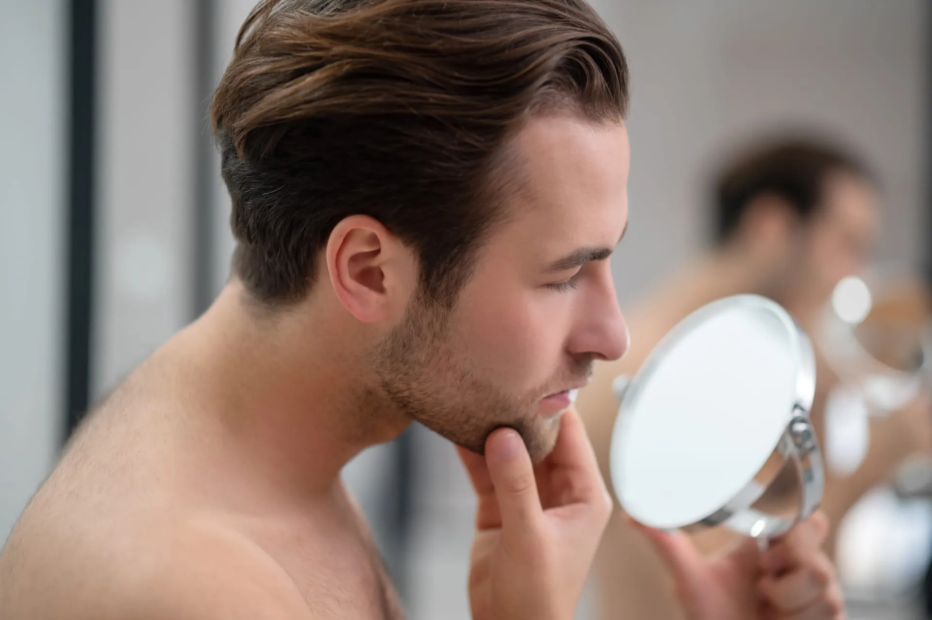 Man bekijkt zijn baard in een handspiegel