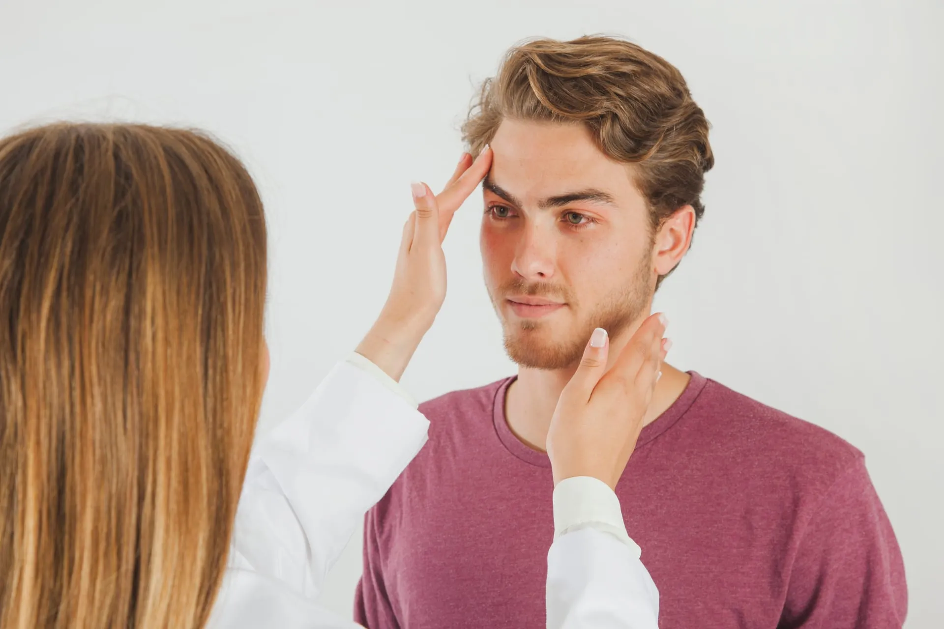 Arts onderzoekt het gezicht van een man met baard