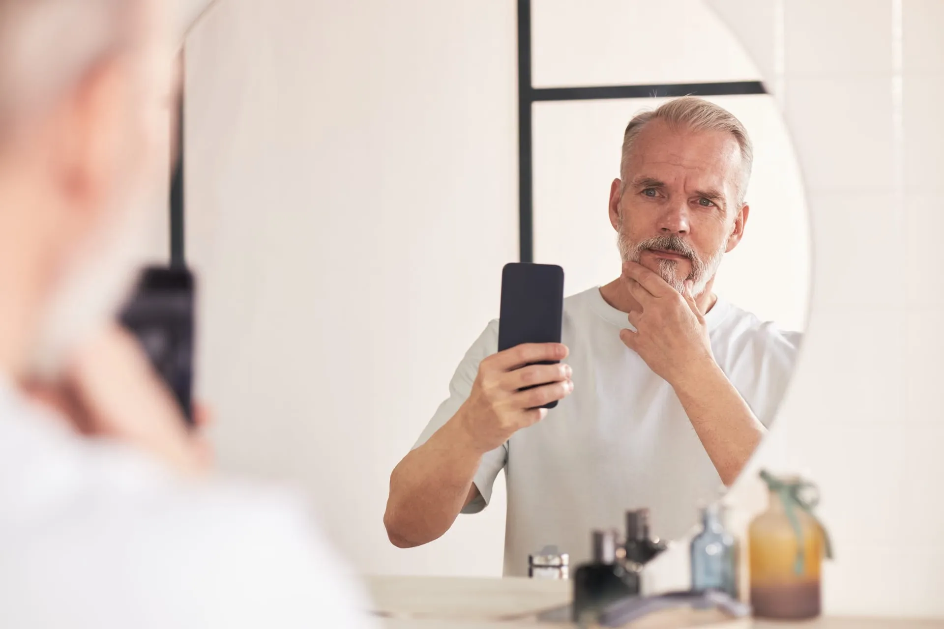 Man fotografeert zichzelf met zijn telefoon in de badkamerspiegel