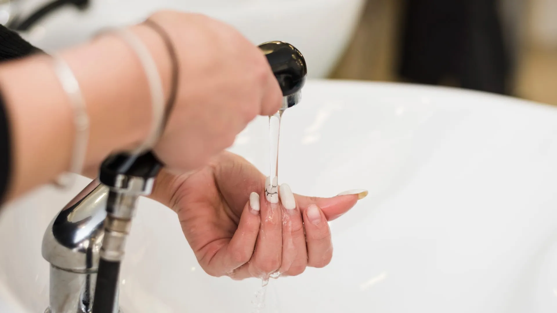 Hand controleert de watertemperatuur onder de douchekop